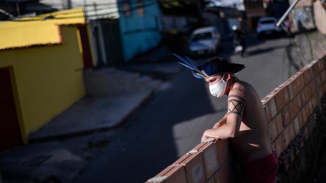 Seorang anggota kelompok etnis Pataxo Hahahae mengenakan masker di Vila Vitoria favela di pinggiran Belo Horizonte, negara bagian Minas Gerais, Brasil, pada 8 Juli 2020 di tengah pandemi coronavirus novel COVID-19.  (AFP/Douglas Magno)