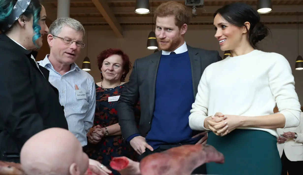 Raut wajah Pangeran Harry dan Meghan Markle saat melihat beberapa anggota tubuh buatan atau prostetik di Catalyst Inc, Belfast, Irlandia Utara, Jumat (23/3). Prostetik tersebut dibuat oleh perusahaan Titanic FX. (Niall Carson/Pool via AP)