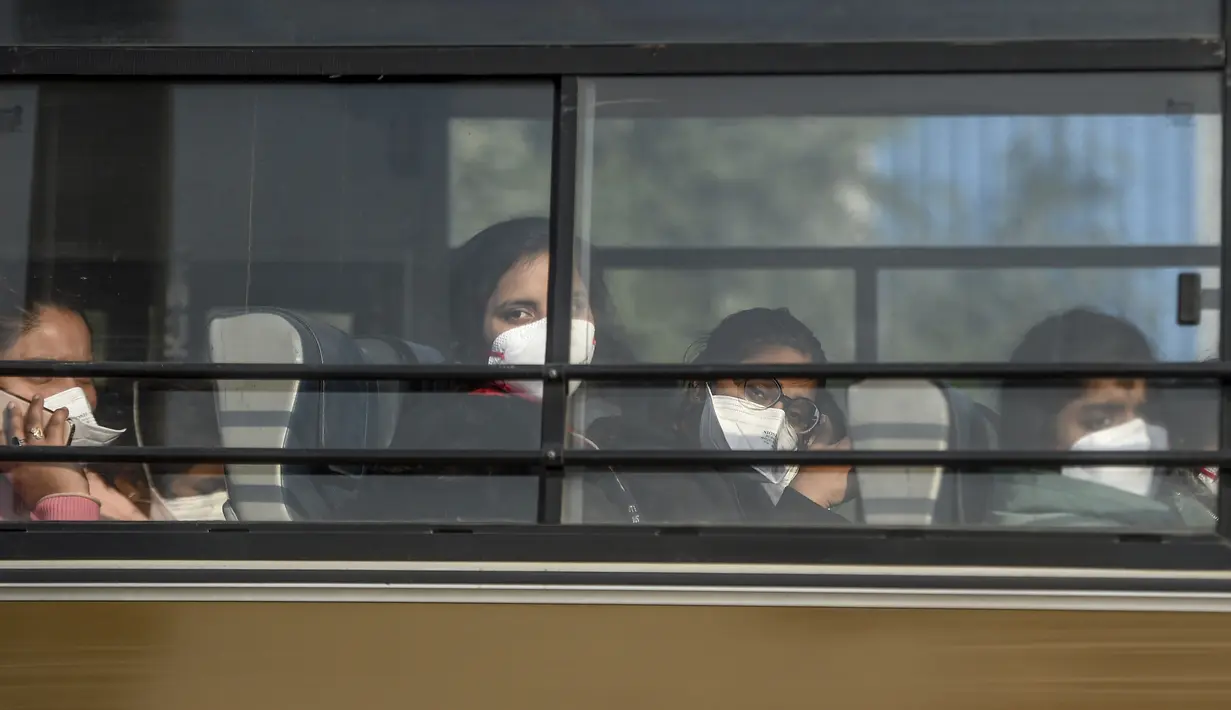 Sejumlah wanita India berada di dalam bus saat keluar dari Bandara Internasional Indira Gandhi setelah dievakuasi dari kota Wuhan di China, di New Delhi (1/2/2020). India mengevakuasi sekitar 250 warganya dari Wuhan, kota di Hubei yang merupakan pusat wabah virus corona. (AFP/Money Sharma)
