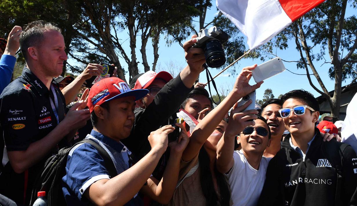 Pebalap Manor F1 Team, Rio Haryanto melayani foto selfie bersama fans sebelum balapan perdana Formula One Australian Grand Prix, Melbourne, Minggu (20/3/2016). (AFP/Paul Crock)