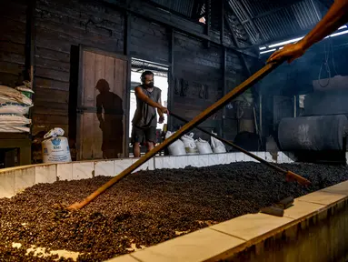 Para pekerja menyebarkan biji kopi robusta setelah disangrai secara tradisional di sebuah pabrik biji kopi kecil di Banda Aceh (14/11/2020). (AFP/Chaideer Mahyuddin)