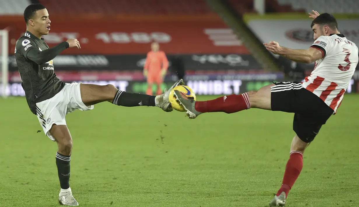 Gelandang Manchester United, Mason Greenwood (kiri) berebut bola dengan pemain Sheffield United, Enda Stevens pada pertandingan Liga Inggris di stadion Bramall Lane, Inggris, Jumat (18/12/2020).  MU bersusah payah mengamankan tiga angka dari tim juru kunci Sheffield United. (AP Photo/Peter Powell)
