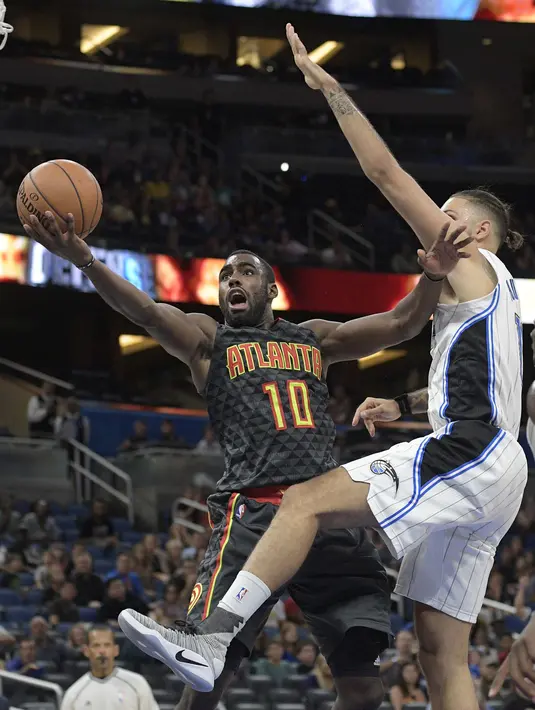 Aksi Pemain Atlanta Hawks, Tim Hardaway, Jr. #10 melakukan layup saat dihadang pemain Orlando Magic, Evan Fournier pada laga NBA preseason basketball game di Orlando, (17/10/2016) WIB. (AP/Phelan M. Ebenhack)