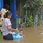 Warga beraktivitas di tengah banjir yang melanda kawasan Cipinang Melayu, Jakarta Timur, Jumat (19/2/2021). Banjir di kawasan tersebut akibat curah hujan yang tinggi dan meluapnya air dari Kali Sunter. (Liputan6.com/Herman Zakharia)