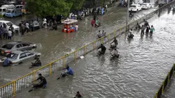 Para pengendara mendorong kendaraannya saat melewati jalan yang banjir di Karachi, Pakistan, Kamis (23/9/2021). Banjir merendam Karachi setelah diguyur hujan deras. (AP Photo/Fareed Khan)