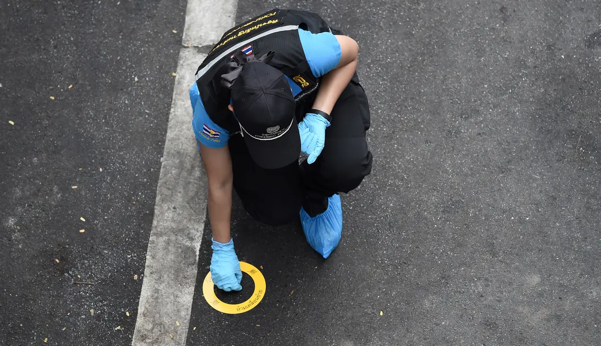 Seorang polisi melakukan penyelidikan di tempat ledakan di Bangkok (2/8/2019). Polisi setempat menduga ledakan bersumber dari benda yang diduga seperti bom rakitan di Distrik Suan Luang. Polisi kini masih menyelidiki penyebab ledakan low explosive itu. (AFP Photo/Lillian Suwanrumpha)