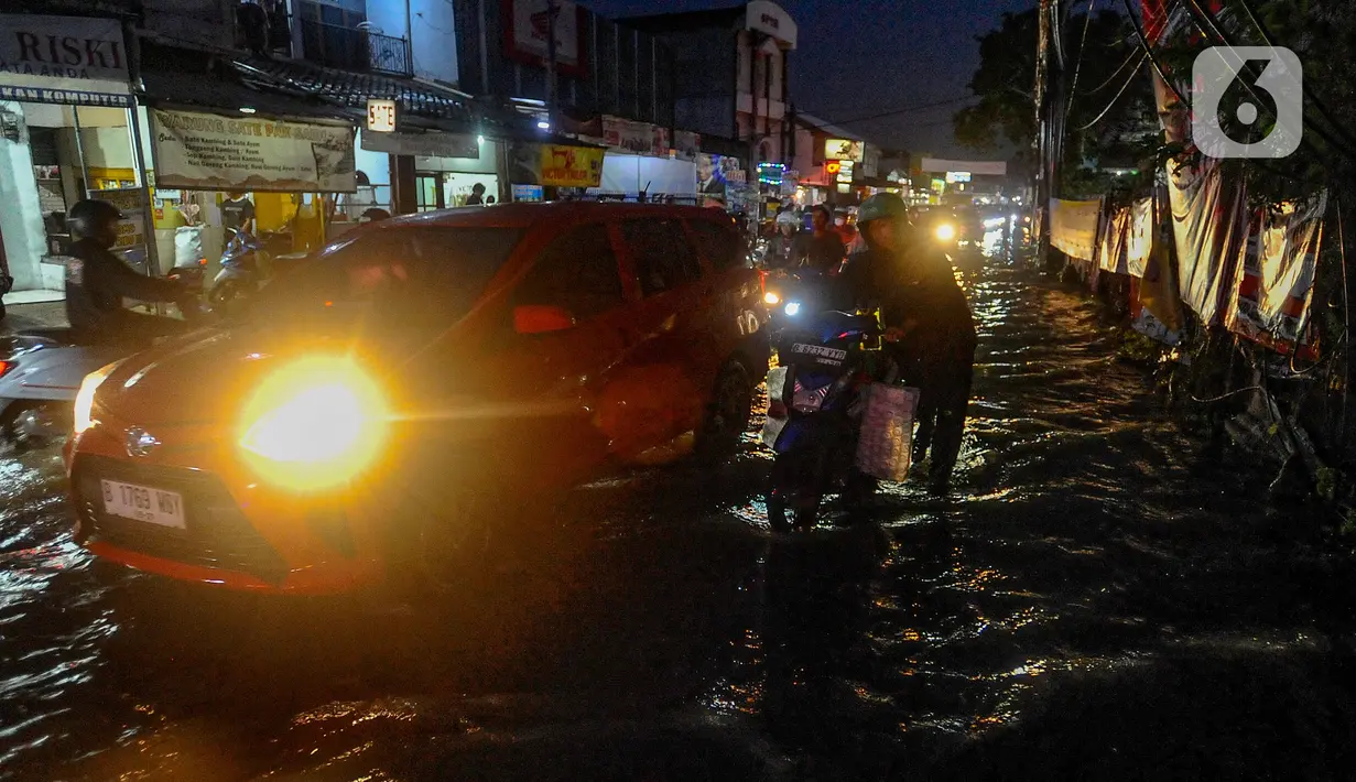 Pengendara mendorong motornya melewati genangan air di kawasan Jalan Dr. Setiabudi, Pamulang, Tangerang Selatan, Rabu (6/12/2023). (merdeka.com/Arie Basuki)