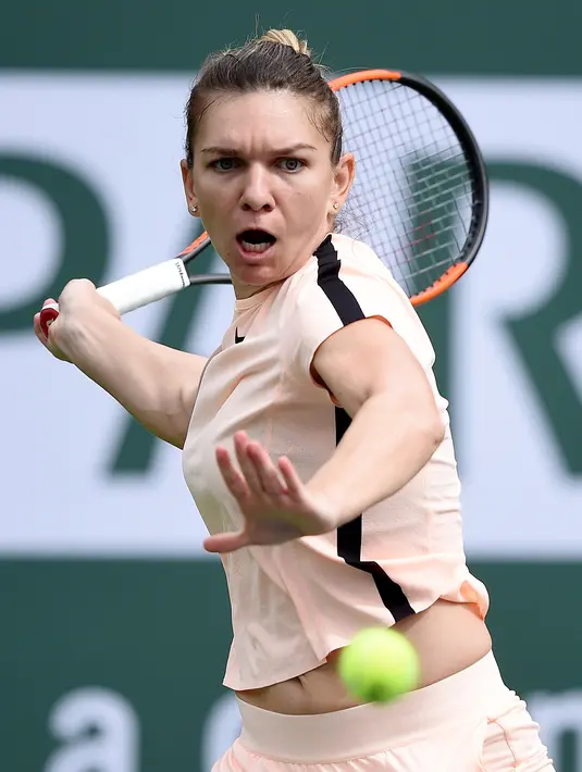 Petenis putri nomor satu dunia, Simona Halep melakukan servis ke arah petenis Cina, Wang Qiang pada turnamen BNP Paribas Terbuka di Indian Wells, Selasa (13/3). Halep mengalahkan pendatang baru Wang Qiang 7-5 6-1. (Kevork Djansezian/Getty Images/AFP)