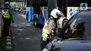 Polisi lalu lintas berkomunikasi dengan pengendara mobil saat Operasi Zebra Jaya 2022 di Jakarta, Selasa (4/10/2022). Operasi Zebra Jaya dilaksanakan pada tanggal 3 hingga 17 Oktober untuk menekan jumlah pelanggaran lalu lintas. (Liputan6.com/Faizal Fanani)