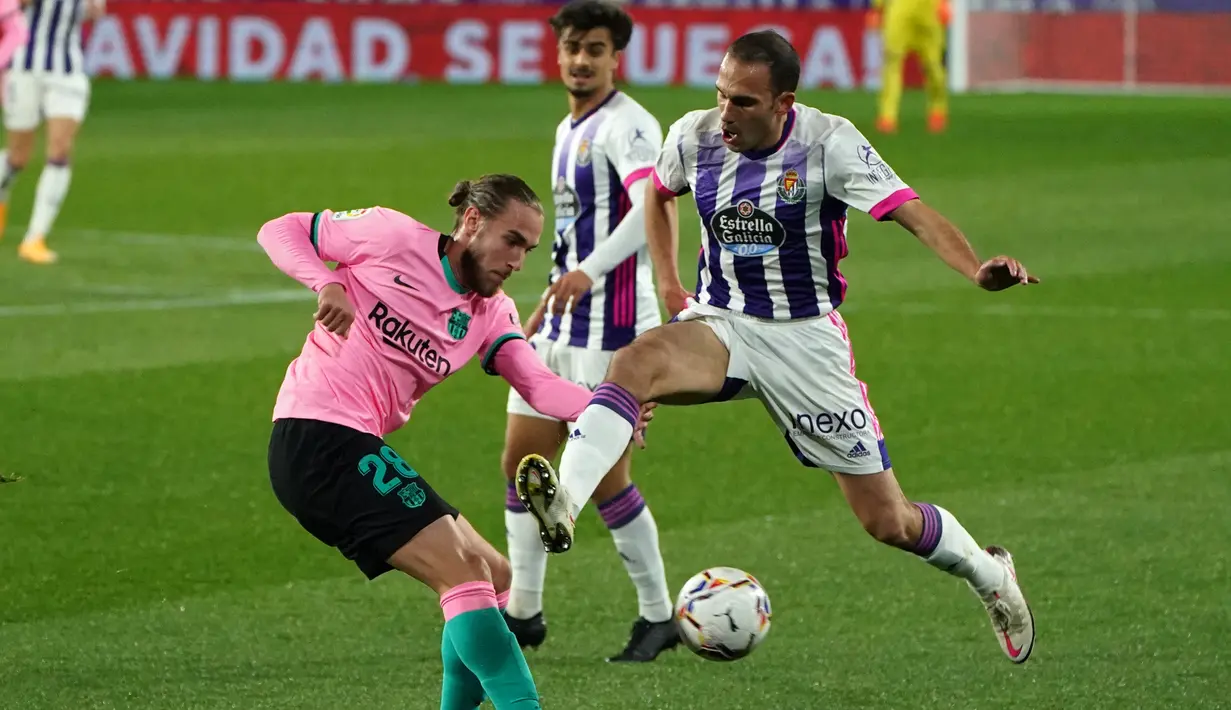 Bek Barcelona, Oscar Mingueza, berebut bola dengan bek Valladolid, Nacho Martinez, pada laga lanjutan Liga Spanyol di Jose Zorrilla Stadium, Rabu (23/12/2020) dini hari WIB. Barcelona menang 3-0 atas Valladolid. (AFP/Cesar Manso)