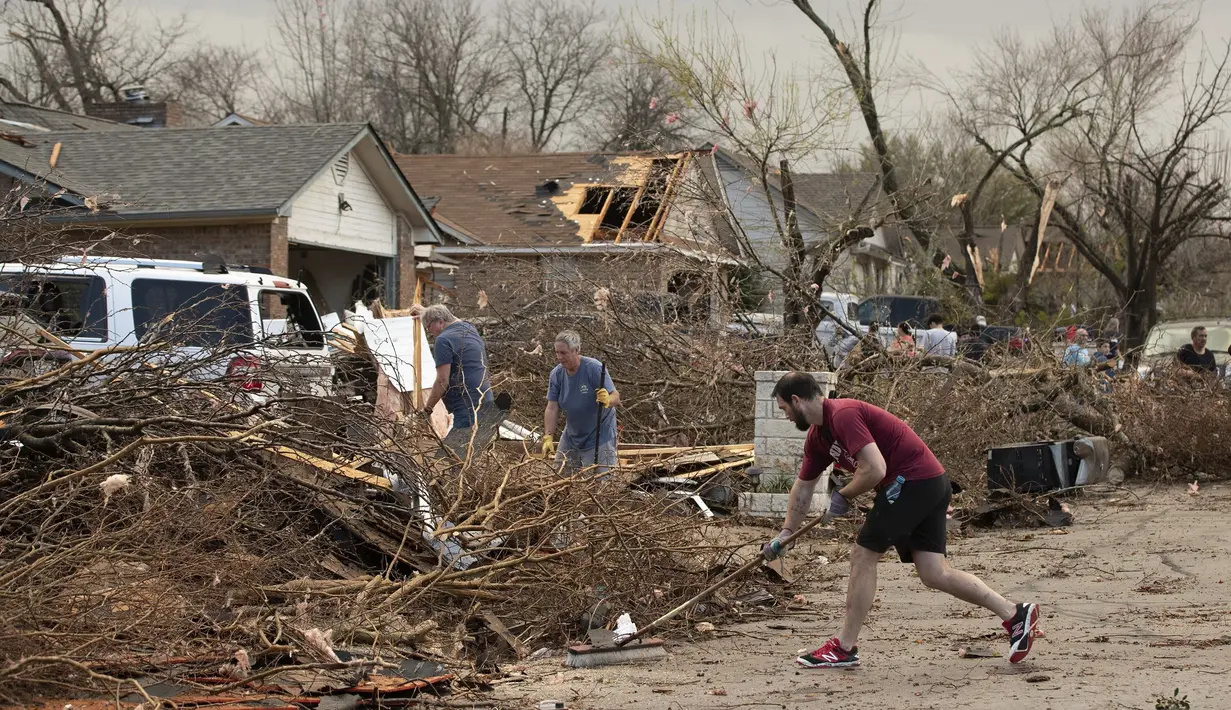 Jarrod Schneider, yang tinggal di Oxford Drive di Round Rock, Texas, membantu tetangganya membersihkan setelah tornado merusak beberapa rumah di jalan, Senin (21/3/2022). (Jay Janner/Austin American-Statesman via AP)
