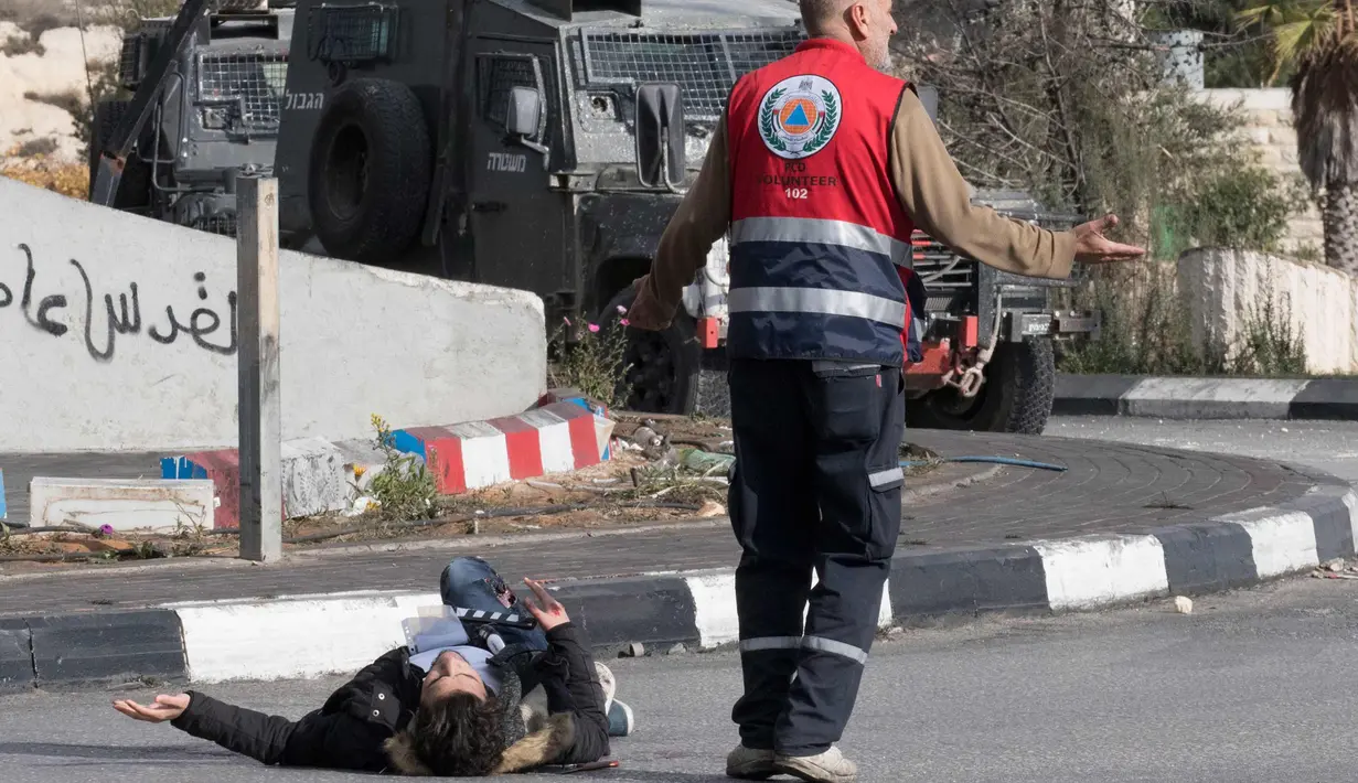 Seorang pria Palestina terjatuh usai ditembak dari jarak dekat oleh polisi Israel di dekat Ramallah, Tepi Barat, Jumat (15/12). Pemuda ini ditembak usai menikam tentara perbatasan Israel. (AFP Photo/Oren Ziv)