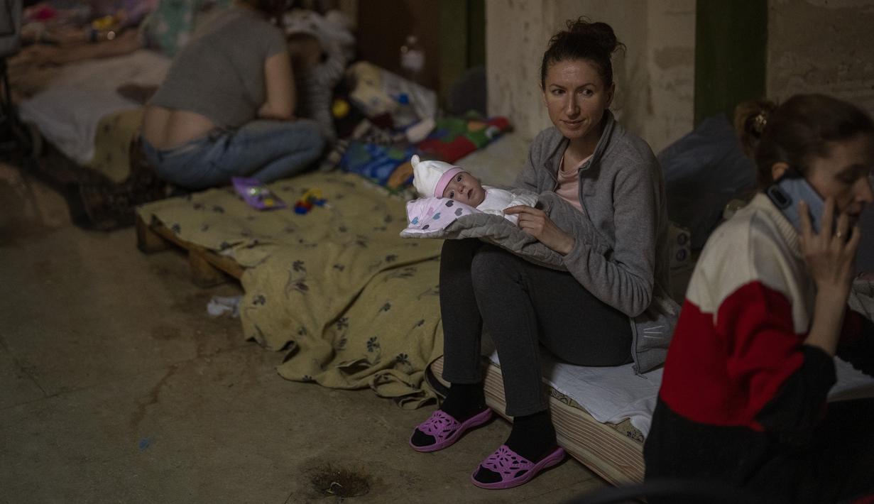 Seorang perempuan menggendong bayinya yang baru lahir di dalam ruang bawah tanah yang digunakan sebagai tempat perlindungan bom di rumah sakit anak Okhmadet di Kiev tengah, Ukraina, Senin (28/2/2022). Hingga kini invasi militer Rusia ke Ukraina terus berlanjut. (AP Photo/Emilio Morenatti)