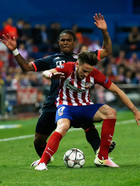 Gelandang Atletico Madrid, Saul Niguez (depan) mengontrol bola dari kawalan gelandang Muenchen, Douglas Costa di leg pertama liga champions di Vicente Calderon, Madrid, (28/4). Atletico menang atas Muenchen dengan skor 1-0. (Reuters/Sergio Perez)
