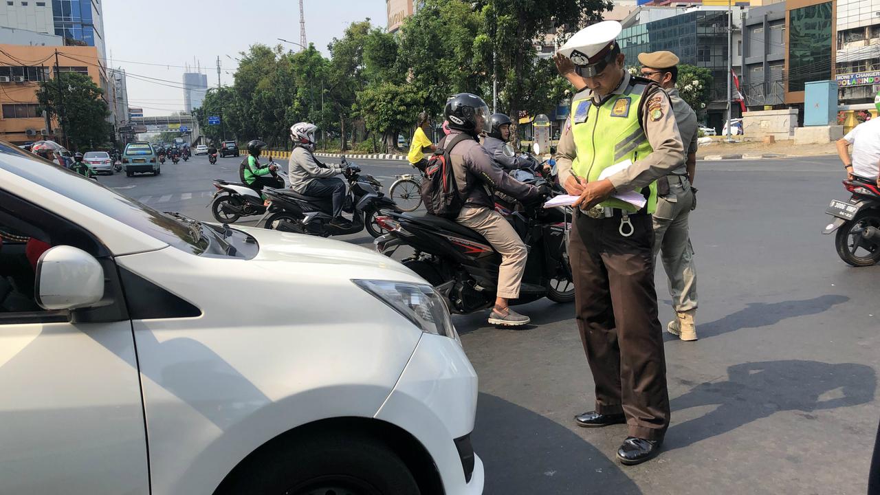 Polisi menindak pelanggar aturan ganjil genap di Jalan Hayam Wuruk dan Jalan Gajah Mada, Jakarta Barat.