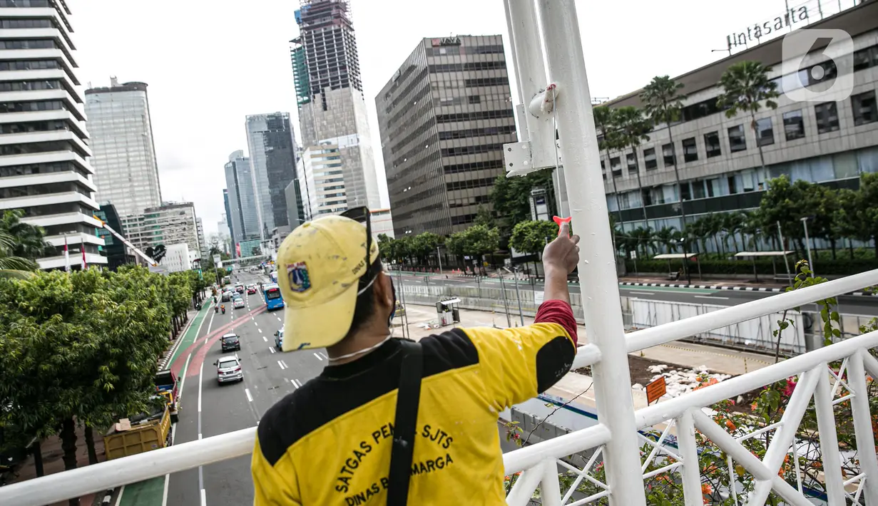 Kesibukan pekerja saat melakukan pengecatan ulang tiang Jembatan Penyeberangan Orang (JPO) di kawasan Thamrin, Jakarta, Kamis (28/1/2021). Pengecatan ulang tersebut dilakukan untuk merawat dan memelihara keberadaan fasilitas umum tersebut. (Liputan6.com/Faizal Fanani)