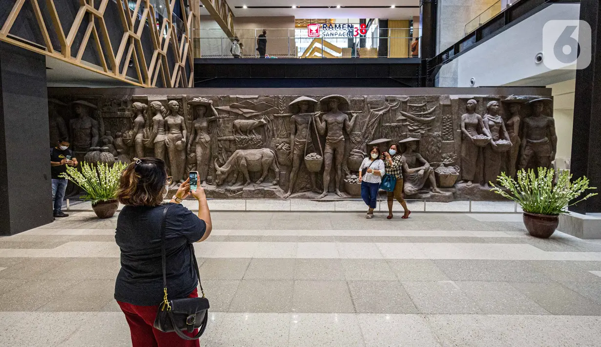 Pengunjung berfoto dengan relief peninggalan Bung Karno di pusat perbelanjaan Sarinah di Jakarta, Senin (21/3/2022). Relief bersejarah peninggalan Presiden pertama RI, IR Soekarno tersebut menjadi daya tarik pengunjung saat beroperasi kembalinya Sarinah hari ini. (Liputan6.com/Faizal Fanani)