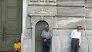Pensiunan menunggu di depan pintu masuk Bank Nasional untuk menerima bagian dari dana pensiun mereka di Athena, Yunani (9/7/2015). Banyak bank di Yunani tutup dan penarikan uang tunai dari ATM dibatasi hanya 67 dolar sehari. (REUTERS/Jean Paul Pelissier)