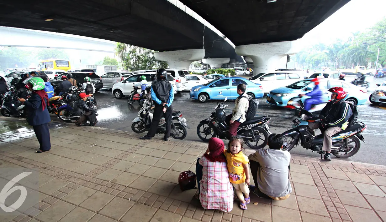 Sejumlah orang saat berteduh di bawah flyover saat hujan turun, Jakarta, Senin (16/11). Memasuki musim hujan, polisi meminta pengendara untuk tidak berteduh di sembarang tempat, khususnya di bawah fly over. (Liputan6.com/Immanuel Antonius)