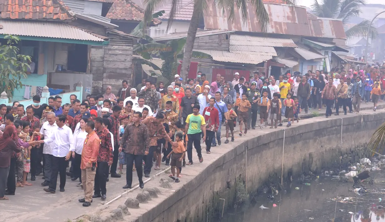 Presiden Jokowi (tengah) didampingi Gubernur Sumsel Alex Nordin dan Menko PMK Puan Maharani disambut warga saat meninjau rumah evakuasi balita yang terkena dampak kabut asap di kawasan 5 Ulu, Palembang, Sumsel, Jumat (30/10). (Laily Rachev_Setpres)