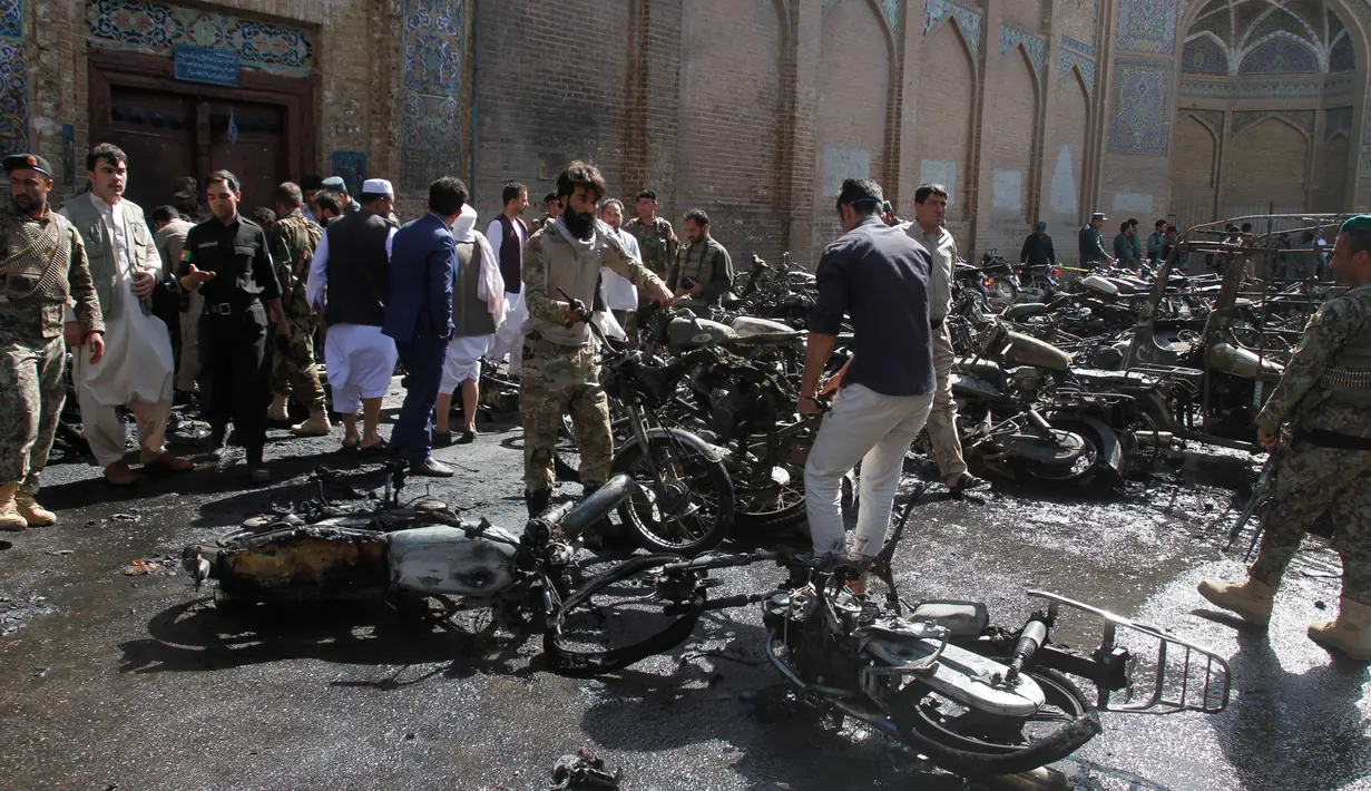 Sejumlah pria memindahkan bangkai motor yang hangus terbakar dalam ledakan bom di luar sebuah masjid bersejarah di kota Herat, Afghanistan, Selasa (6/6). Ledakan ini menyebabkan tujuh orang tewas dan 15 lainnya terluka. (AP Photos/Hamed Sarfarazi)