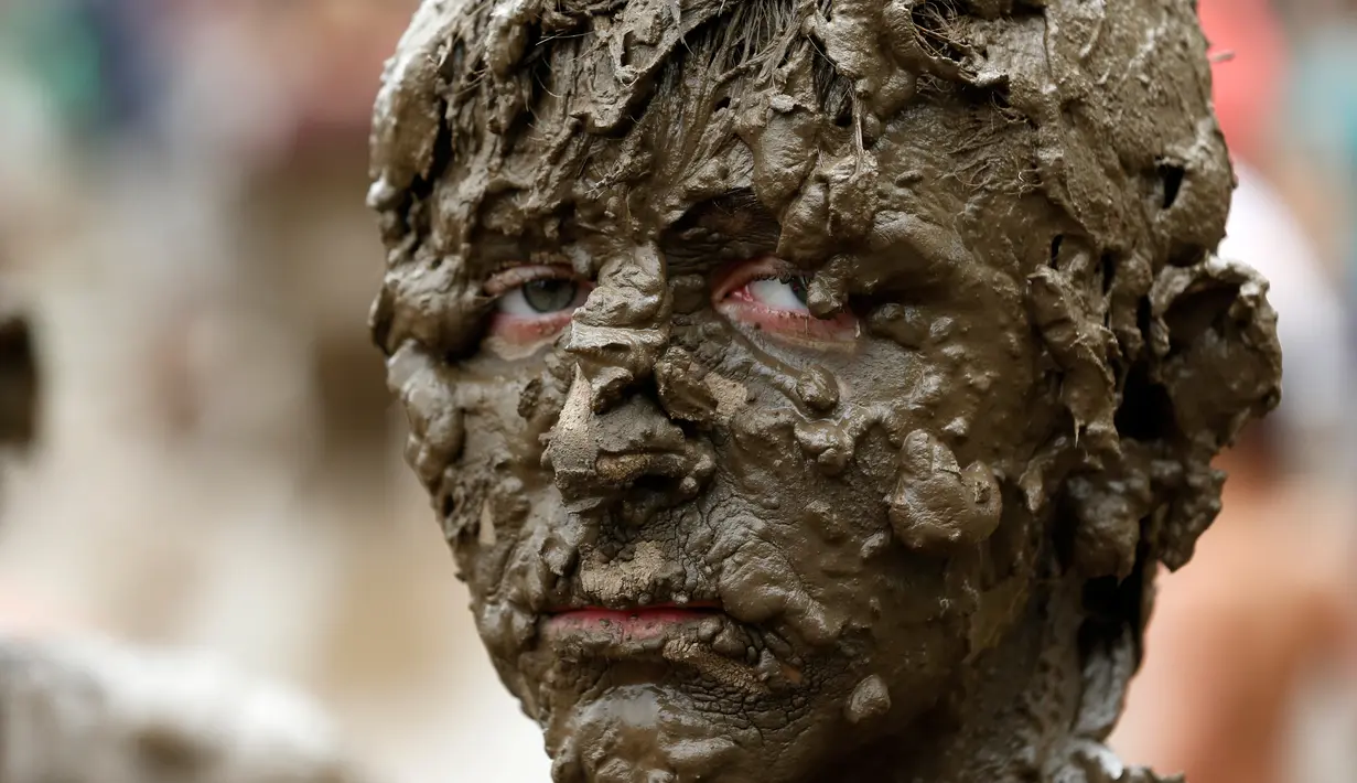 Ekspresi seorang anak yang penuh lumpur saat berpartisipasi dalam perayaan Mud Day atau Hari Lumpur di Wayne County di Nankin Mills Park, Westland, Michigan, AS (11/7). (AFP Photo/Jeff Kowalsky)