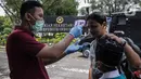 Petugas memeriksa suhu tubuh orang-orang yang akan memasuki Kompleks Istana Kepresidenan, Jakarta, Selasa (3/3/2020). Istana Kepresidenan memperketat pemeriksaan terhadap tamu, ASN, dan pejabat negara untuk mencegah penyebaran virus corona (COVID-19). (Liputan6.com/Faizal Fanani)