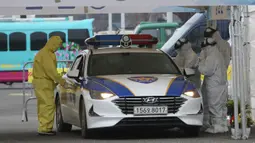 Petugas medis dengan pakaian pelindung mengambil sampel dari pengemudi di layanan "drive-thru" di Goyang, Korea Selatan, 1 Maret 2020. Drive thru (tanpa turun) virus Corona COVID-19 diberlakukan karena permintaan layanan tes kesehatan melonjak.  (AP/Ahn Young-joon)