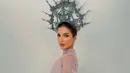 Dari samping, siluet gaun satin yang dililit anggun di bagian rok terlihat jelas. Lengan renda lilac yang menjuntai panjang menambah kesan dramatis, sementara crown silver bergaya halo dengan ornamen filigree dan mutiara membingkai kepalanya. [@tasyafarasya]