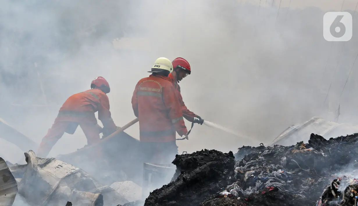 Petugas pemadam kebakaran melakukan pendingin di Pabrik penggilingan kapas,  Pasar Rebo, Jakarta Timur, Selasa (16/11/2021). Api melalap Pabrik penggilingan kapas yang di sebabkan korsleting pada panel listrik. (Liputan6.com/Herman Zakharia)