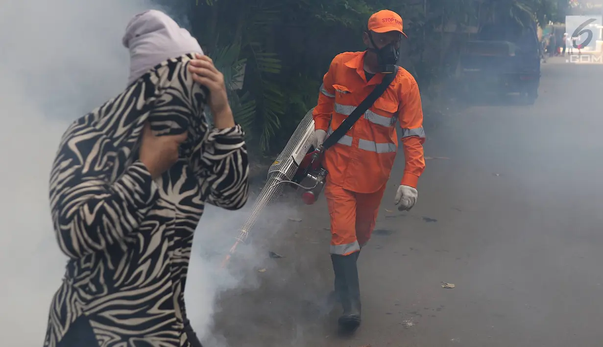 Seorang warga menutup wajah saat petugas melakukan pengasapan (fogging) di kawasan Kebon Baru, Tebet, Jakarta, Kamis (28/2). Pengasapan dilakukan terkait adanya warga di kawasan itu yang terkena penyakit demam berdarah. (Liputan6.com/Immanuel Antonius)