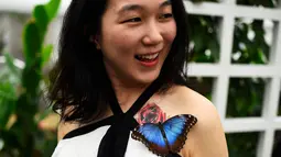 Seorang pengunjung yang merupakan wartawan TV Jepang tersenyum saat mengetahui kupu-kupu hinggap di tato bunga tubuhnya pada pameran Sensasional Butterflies di Museum Sejarah Alam,London, Inggris 23 Maret 2016. (REUTERS / Dylan Martinez)