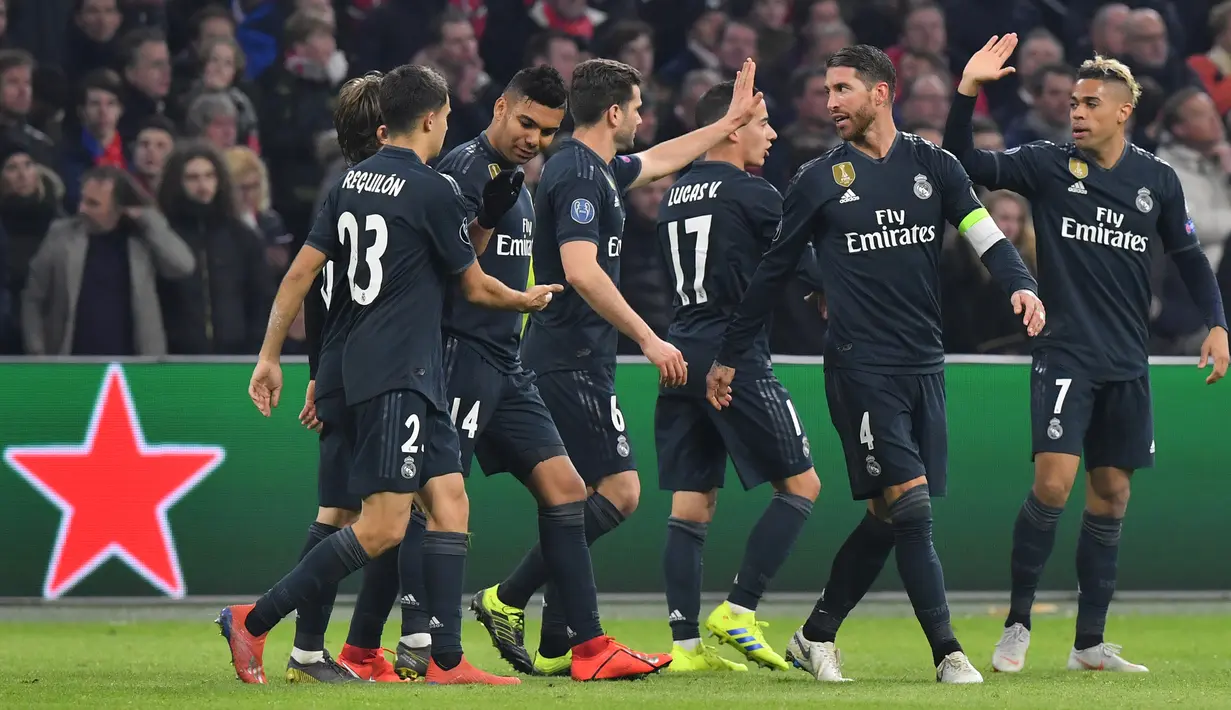 Para pemain Real Madrid merayakan gol kedua tim mereka ke gawang Ajax pada leg pertama 16 besar Liga Champions di Johan Cruijff ArenA, Amsterdam, Rabu (13/2). Real Madrid harus bersusah payah menaklukkan Ajax dengan skor tipis 2-1. (EMMANUEL DUNAND/AFP)