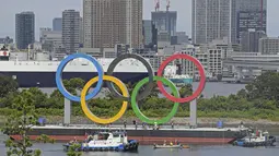 Para pekerja bersiap melepas cincin Olimpiade yang mengambang di air setelah Olimpiade Musim Panas 2020 berakhir pada 8 Agustus, di Tokyo, Rabu (11/8/2021). Setelah ini, Kota Paris, Prancis, akan menjadi tuan rumah olimpiade pada 2024 mendatang. (Kyodo News via AP)