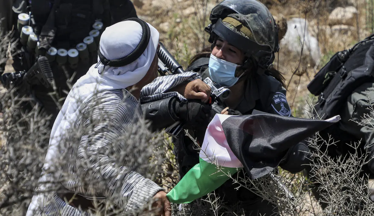 Tentara Israel mengamankan seorang pengunjuk rasa Palestina yang memprotes pembukaan lahan untuk permukiman Israel di dekat Desa Shoufah, wilayah Tepi Barat (20/8/2020). (AFP/JAAFAR ASHTIYEH)