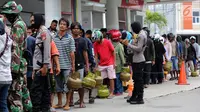 Aparat polisi menjaga antrean operasi pasar elpiji di SPBU Ki Hajar Dewantara di Palu, Sulawesi Tengah, Senin (8/10). Pertamina melakukan operasi pasar elpiji pascagempa dan tsunami Palu di 16 titik di Palu, Donggala dan Sigi (Liputan6.com/Fery Pradolo)
