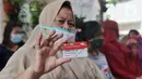 Warga menunjukkan Kartu Warga Sejahtera saat mengantre sembako BPNT di RW 01 Kelurahan Gaga,Larangan, Kota Tangerang, Banten, Rabu (24/2/2021). Bantuan tersebut senilai Rp 200.000 yang dibelanjakan 12 kg beras, 1 kg telur, tempe, sayuran dan buah. (Liputan6.com/Angga Yuniar)