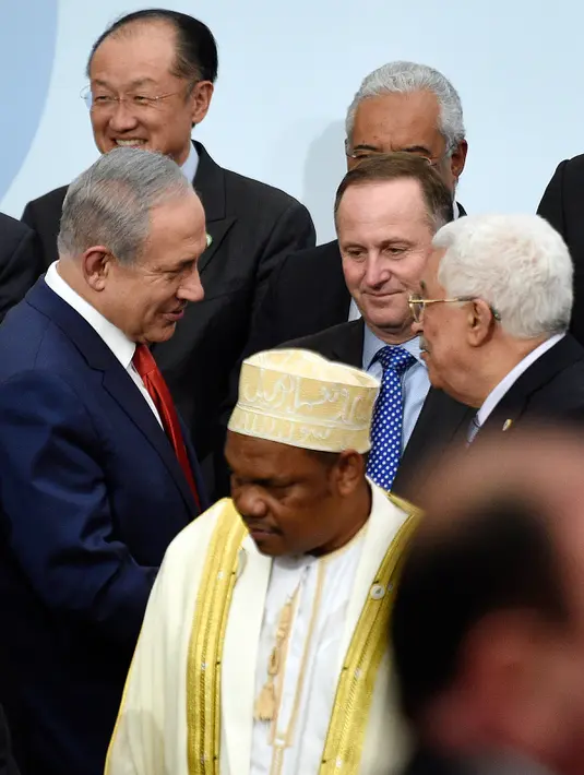 PM Israel Benjamin Netanyahu (kiri) berjabat tangan dengan Presiden Palestina Mahmud Abbas di depan Presiden Selandia Baru disela foto bersama pada KTT Perubahan Iklim, Conference of Parties (COP) 21 di Prancis, Senin (30/11). (AFP/POOL/MARTIN BUREAU)