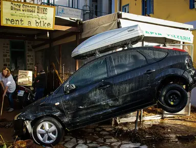 Sebuah mobil di depan toko rental kendaraan rusak akibat diterjang banjir bandang yang melanda pulau Symi di Yunani, Rabu (15/11). Banjir bandang itu melanda tiga kota terpisah di Negeri Dewa tersebut. (Argiris Madikos /Eurokinissi via AP)