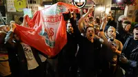 Pendukung Liverpool bernyanyi dan melambai-lambaikan bendera tim mereka di sebuah pub di alun-alun Campo de 'Fiori Roma, Italia (1/5). Liverpool akan menghadapi AS Roma di leg kedua semifinal Liga Champions. (AP Photo/Andrew Medichini )