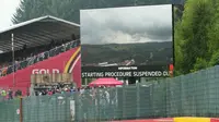 Layar besar menampilkan pemandangan umum lintasan dengan awan hujan dan pesan "Prosedur start ditangguhkan" sebelum dimulainya Grand Prix Formula Satu Belgia di sirkuit Spa-Francorchamps di Spa, pada 27 Juli 2025. (Dimitar DILKOFF /AFP)