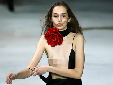 Seorang model berusaha merapikan gaun yang dikenakannya pada peragaan busana Yves Saint Laurent ready-to-wear di Paris, 28 Februari 2017. Gaun model tersebut melorot saat menampilkan koleksi Fall-Winter 2017-2018. (AP/Francois Mori)