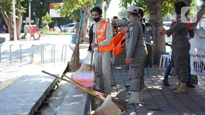 Warga pelanggar PSBB dihukum menyapu fasilitas umum saat terjaring operasi kepatuhan disiplin masker di kawasan Waduk Sunter, Jakarta, Selasa (8/9/2020). Warga yang kedapatan melanggar akan dikenakan sanksi denda Rp 250 ribu atau membersihkan fasilitas umum. (Liputan6.com/Immanuel Antonius)