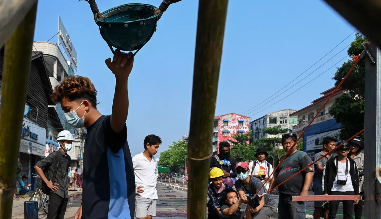 Para pengunjuk rasa menguji senjata ketapel besar ketika pasukan keamanan melanjutkan tindakan keras terhadap demonstrasi menentang kudeta militer di Yangon, Rabu (17/3/2021). (AFP/STR)