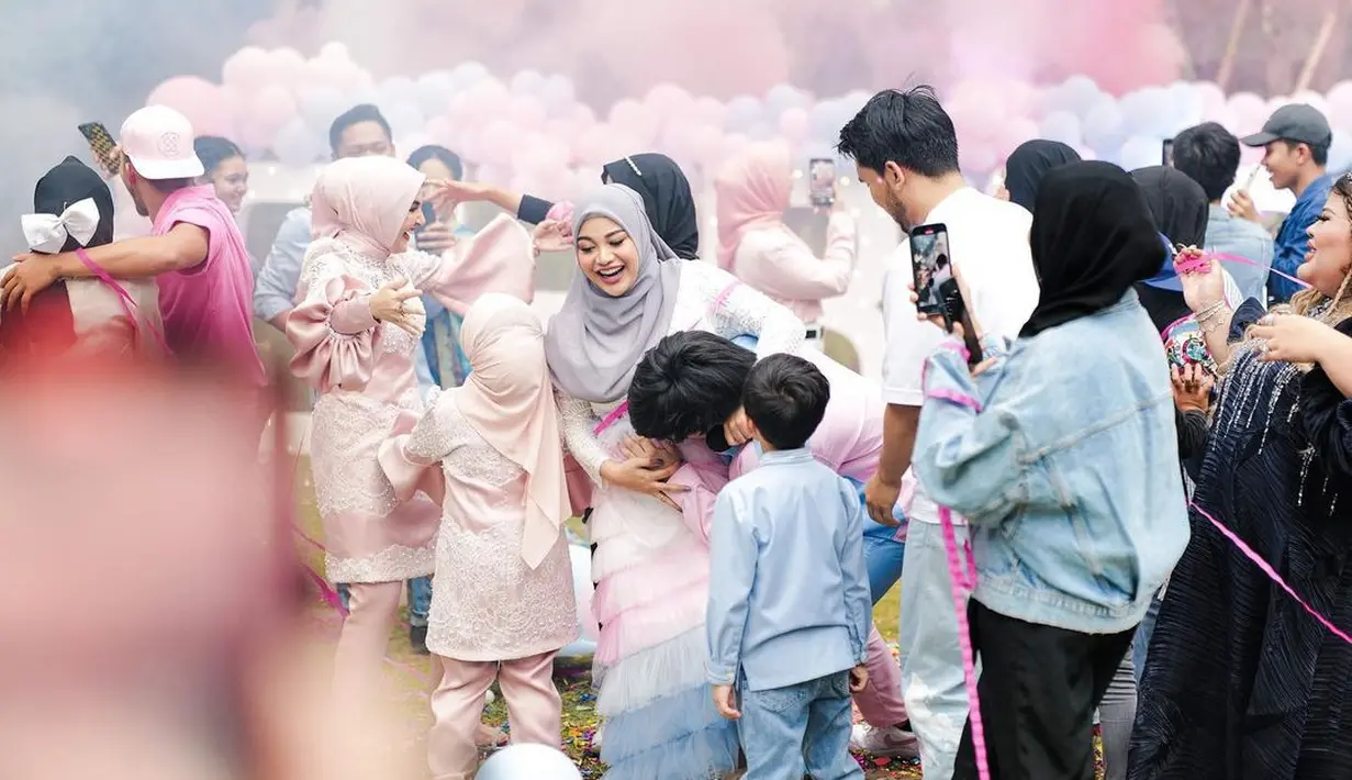 Senada dengan sang istri, Atta tampak mengenakan kemeja nuansa biru-pink.