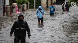 Warga melintasi banjir di jalan Pd. Karya, Jakarta, Kamis (13/12). Hujan yang mengguyur Jakarta Sore tadi menyebabkan banjir setinggi 40cm  menggenangi kawasan Jalan Pd. Karya dan Jalan Bangka. (Liputan6.com/Faizal Fanani)