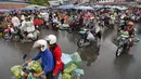 Orang-orang mengendarai sepeda motor melewati pasar di Phnom Penh (24/7/2020). Pasar membentuk bagian integral dalam kehidupan orang Kamboja, dengan kunjungan harian yang dilakukan untuk persediaan makanan untuk hari itu serta barang-barang lainnya. (AFP/Tang Chhin Sothy)