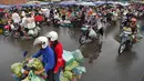 Orang-orang mengendarai sepeda motor melewati pasar di Phnom Penh (24/7/2020). Pasar membentuk bagian integral dalam kehidupan orang Kamboja, dengan kunjungan harian yang dilakukan untuk persediaan makanan untuk hari itu serta barang-barang lainnya. (AFP/Tang Chhin Sothy)