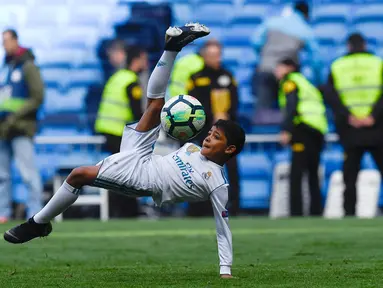 Anak Cristiano Ronaldo, Cristiano Ronaldo Jr melakukan tendangan salto usai pertandingan antara Real Madrid dan Atletico Madrid di stadion Santiago Bernabeu, Madrid (8/4). Anak Ronaldo melakukan tendangan salto meniru sang ayah. (AFP Photo/Gabriel Bouys)