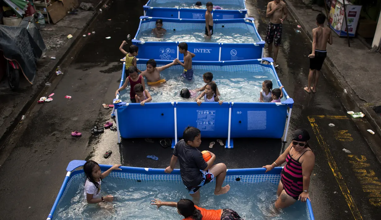 Anak-anak didampingi orang tua bermain di kolam portabel yang diberikan oleh pemerintah setempat untuk mendinginkan tubuh pada saat musim panas di Manila, Filipina (12/4). (AFP Photo/Noel Celis)